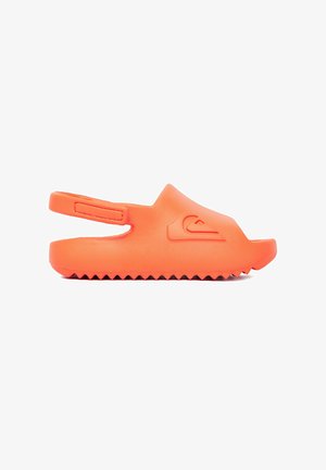 Jasno pomarańczowy sandał wsuwany z paskiem z tyłu, teksturowaną podeszwą i wytłoczonym logo na górze, pokazany z boku na białym tle.