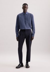 Marineblauw patroon overhemd met een spreidkraag, gecombineerd met op maat gemaakte donkere broek en zwarte veterschoenen.