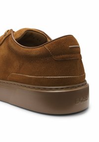 Chaussure décontractée pour homme en daim marron avec semelle épaisse en caoutchouc, détails de couture et logo "BOSS" embossé sur le talon.