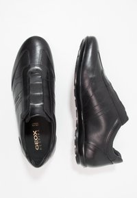 Fekete bőr slip-on cipők sima felülettel, rugalmas oldalsó panelek, textúrázott díszítések és tartós gumitalp jellemzi őket.