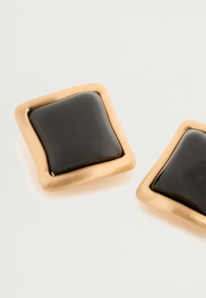 Boucles d'oreilles carrées en ton or avec un insert en émail noir poli. Présentent des bords arrondis et une texture de surface lisse.