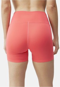 Koral atletiske shorts laget av elastisk stoff, med høy midje, sømløst design og en glatt tekstur med minimal sømdetaljer.