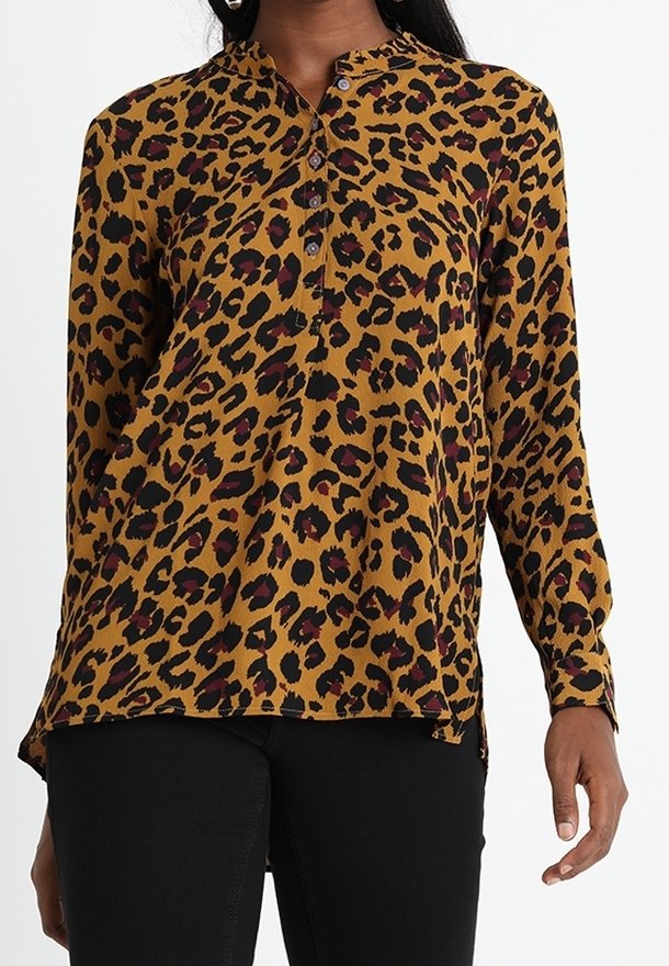 Blusa con stampa leopardata in senape con macchie nere e borgogna, dotata di una chiusura con bottoni e maniche lunghe. Tessuto morbido, vestibilità comoda.