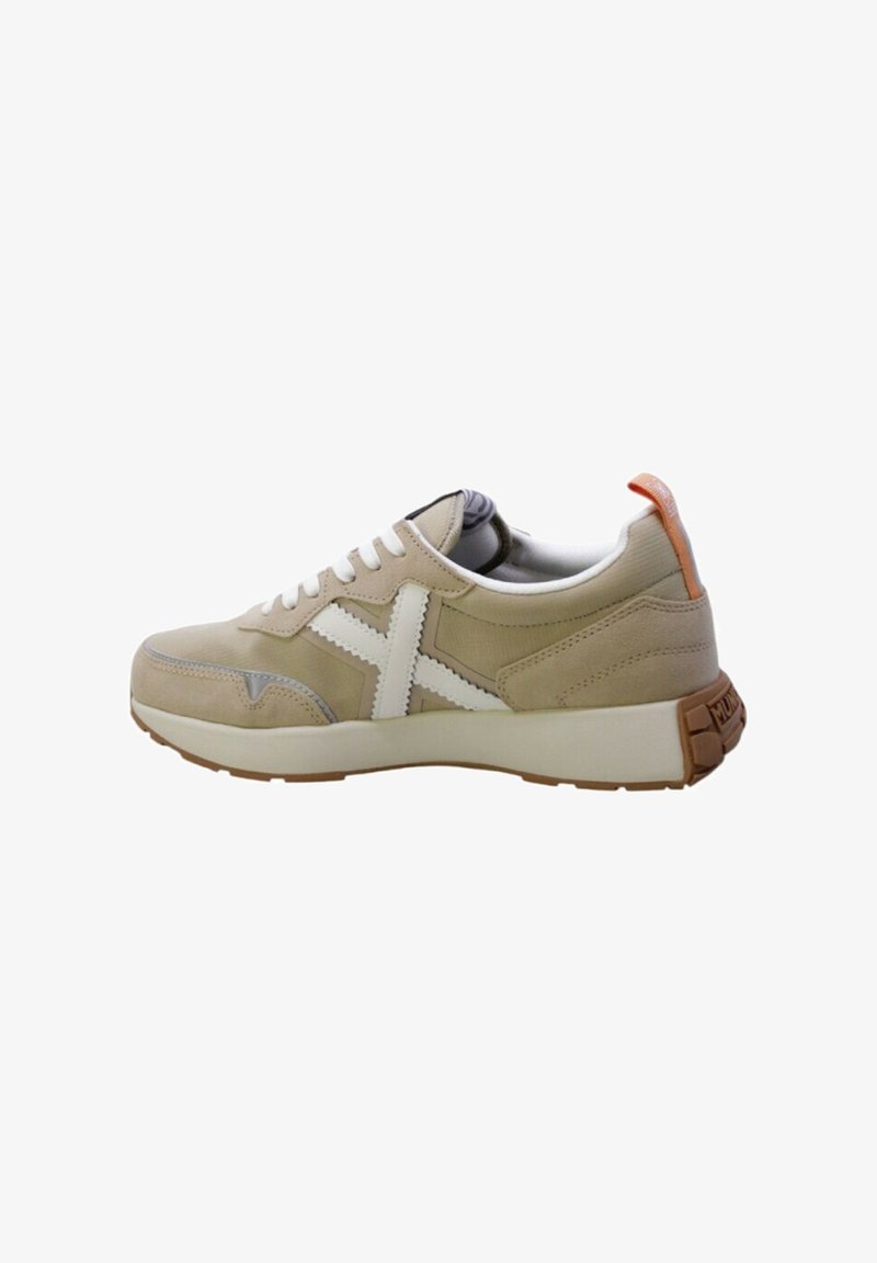 Sneaker beige con accenti bianchi, parte superiore in suede testurizzato e mesh, chiusura con lacci e una spessa intersuola bianca. Presenta una linguetta sul tallone di colore arancione in contrasto.