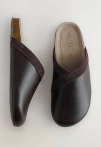 Zuecos de cuero marrón oscuro con un diseño de tiras cruzadas de ante, acabado suave y plantilla de corcho. Forro interior suave que mejora la comodidad.