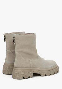 Beige suède enkellaarsjes met een gestructureerde chunky zool, dubbele zijritsen en een soepele binnenvoering. Minimalistisch ontwerp met een lage hoogte.