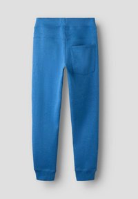 Blå joggingbukser med glat tekstur, elastisk taljebånd og en enkelt baglomme. Mansjetterne er tætsiddende ved anklerne.