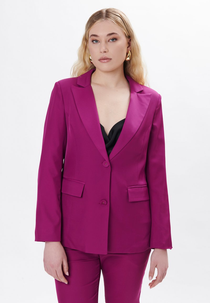 Fuchsia blazer med påsatte revers og enkeltknaplukning, med to frontlommer. Glat, struktureret stof; parret med en sort top.