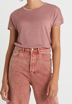 Korte mouw, ronde hals, vervaagde roze t-shirt gecombineerd met hoge taille, lichtroze spijkerbroek met een gestructureerde afwerking en voorzakken.