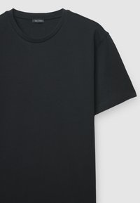 T-shirt nera a maniche corte realizzata in tessuto strutturato, con scollo tondo e vestibilità comoda. Etichetta "CALLIOPE" visibile all'interno.