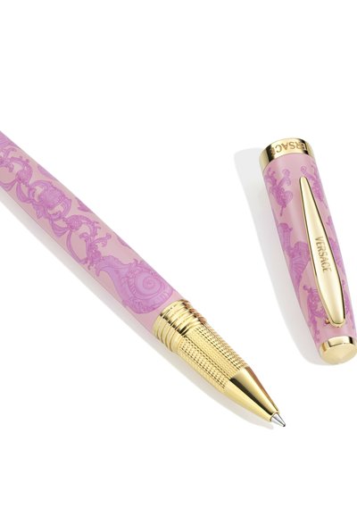 Ružičasta kemijska olovka s zlatnim vrhom i klipsom, ukrašena složenim baroknim uzorcima i natpisom "VERSACE" na kapici.