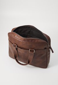 Brown leather bag with a zipper closure, dual top handles, and a black interior. Features front pockets and smooth, textured finish.