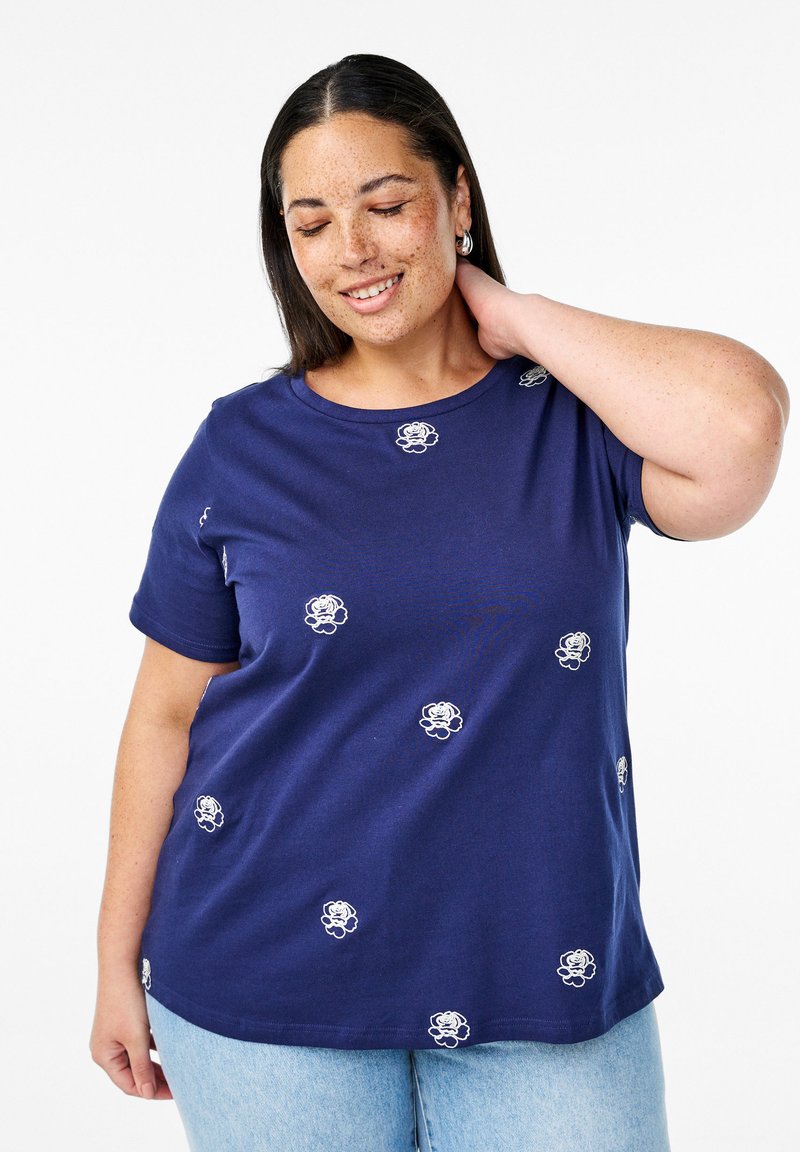 Námořnická bavlněná tričko s krátkým rukávem, s bílými vyšívanými květinovými detaily rozptýlenými po látce. Kulatý výstřih a volný střih.