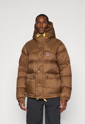 Brown puffer jacket with a hood, yellow drawstrings, two front pockets, and logo patch. Shiny fabric with a quilted texture.