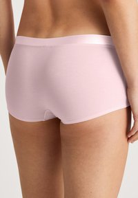 Lichtroze katoen boyshorts met een soepele tailleband, voorzien van een lage snit en een kleine opening aan de achterkant. Zachte textuur en naadloos ontwerp.