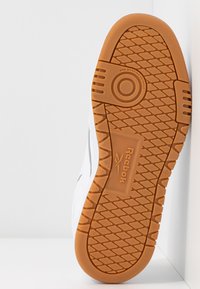 Bela podplata superge z teksturiranim oprijemom, ki ima gumijast zunanji del in logotip "Reebok". Oblikovana je tako, da ne pušča sledi, z okroglimi poudarki.