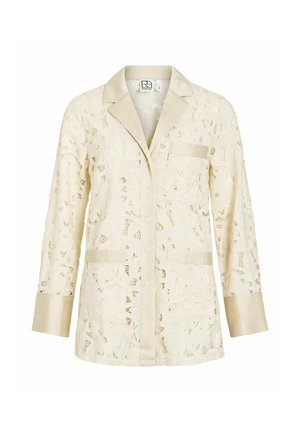 Duga kremasta majica od čipke s ovratnikom i manšetama od satena, prednjim kopčanjem na gumbe te s tri džepa, ukrašena cvjetnim izrezbarenjima.