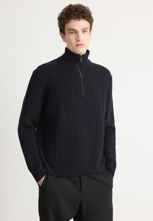 Navy ribbed knit sweater with a stand-up collar and half-zip closure. Long sleeves and relaxed fit, made of soft fabric.