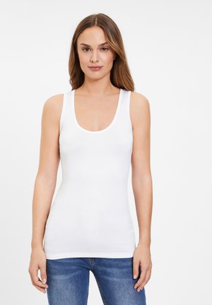 White tank top with a scoop neckline and wide straps, made of smooth, stretchy material. Paired with blue denim jeans.