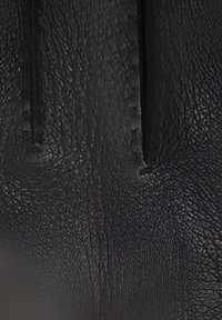 Texture di pelle nera con una finitura grainosa, caratterizzata da pieghe visibili e sottili imperfezioni, che enfatizzano un aspetto robusto e naturale.