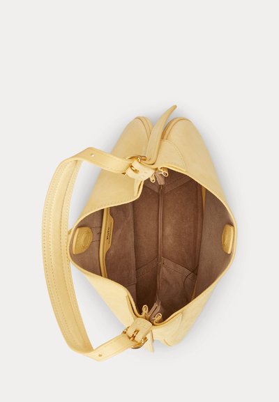Žltá kožená kabelka so zlatými kovaniami, jedným uchom a priestranným hnedým semišovým vnútrom bez obsahu.
