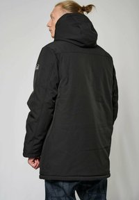 Giacca nera con cappuccio, dal finish liscio e opaco. Presenta un design semplice, cuciture visibili e un piccolo logo sulla spalla sinistra.