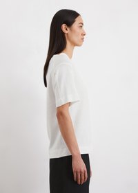 White short-sleeve sweater with a relaxed fit, made of soft fabric. Features a crew neckline and slight ribbing at the hem and sleeves.