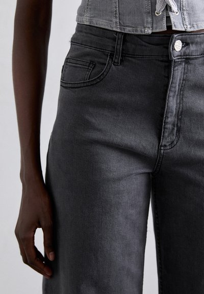Dark gray denim jeans with a high waist, featuring a front pocket, subtle stitching, and a visible metal button closure. Texture appears smooth.