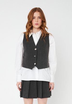 Gray pinstripe vest with silver buttons, layered over a white collared shirt, paired with a matching pleated gray skirt. Cotton blend material.