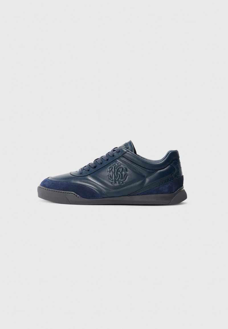 Sneaker albastru marin, cu glezna joasă, cu panouri din piele și suede, logo embosat pe lateral și talpă din cauciuc negru, prezentat din profil lateral.