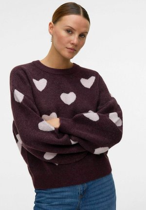 Pull en tricot bordeaux avec des motifs de cœurs blancs, col rond et manches oversize. Présenté avec un ourlet et des poignets côtelés.