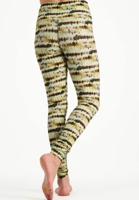 Tajta leggings i ett tie-dye-mönster med gröna, gula och bruna ränder. Materialet verkar slätt med en stretchig textur.