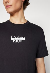 Calvin Klein CUT THROUGH LOGO - Apdrukāts T-krekls - black