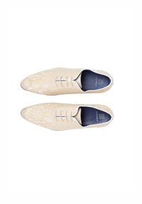 Veterschoenen van crèmekleurige stof met een bloemenpatroon, puntige neusvorm, contrasterende donkere binnenzool en witte stiksels.