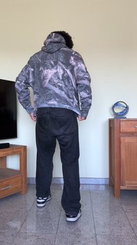 Sweatshirt com capuz em padrão camuflado, com tons de cinza e branco. Combinado com jeans escuros e ténis pretos com detalhes brancos.
