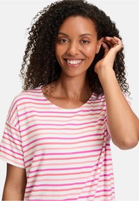 Stribet T-shirt i blødt stof, med rosa og hvide vandrette striber, rund halsudskæring og afslappet pasform. Krøllet hår, der indrammer ansigtet.
