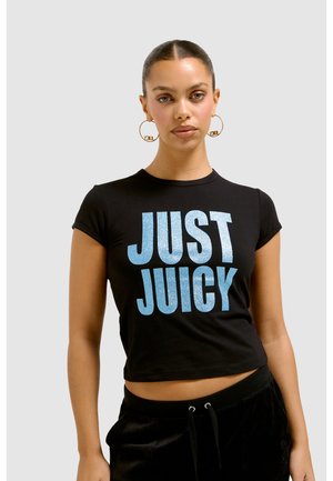 Zwarte korte crop top met korte mouwen, voorzien van grote, glinsterende blauwe letters die "JUST JUICY" spellen. Zacht katoen, eigentijdse pasvorm.