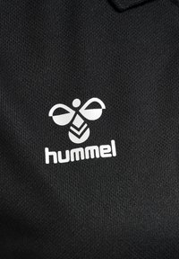 Svart texturerad tyg med en vit hummel-logotyp; har en stiliserad bi-design ovanför varumärkesnamnet i fet, blockbokstäver.