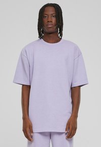 Helllila oversized T-Shirt mit kurzen Ärmeln, hergestellt aus weichem Stoff. Verfügt über einen einfachen, runden Halsausschnitt und einen entspannten Schnitt.