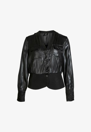 Black blouse with a silky texture, V-neck, two chest pockets, and long sleeves; elastic waist with a solid black bottom and decorative cuffs.