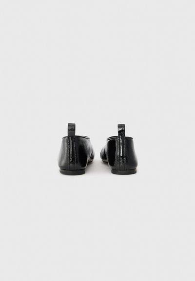 Ballerines en cuir verni noir avec un bout arrondi et un petit talon. Dotées d'un petit onglet au dos et d'une surface lisse et brillante.