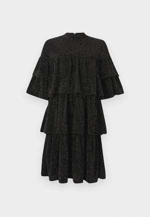 Abito nero a balze con pois bianchi, scollatura alta e maniche corte svasate, esposto su uno sfondo bianco semplice.