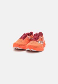 Heldere oranje hardloopschoenen met een bovenwerk van mesh, kastanjebruine accenten en bijpassende veters. Beschikt over een textuurzool voor grip en ondersteuning.