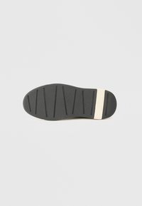 Potplat cipela s crnim gumiranim uzorkom, horizontalnim utorima i bež dijelom peta s utisnutim logotipom "A|X Armani Exchange".