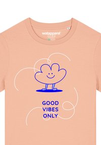 Perzikkleurig katoenen T-shirt met een blauwe cartoonwolk en de tekst "GOOD VIBES ONLY" in vet blauw, met wervelende accenten.