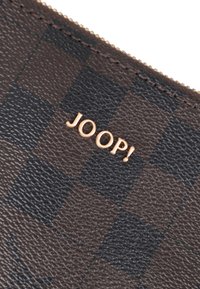 Portafoglio in pelle marrone con motivo a scacchi, impresso con la scritta "JOOP!" in oro, dalla texture liscia e con chiusura a zip.