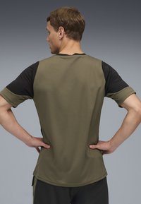 T-shirt med korte ærmer i khaki med sorte ærmer, som har en glat tekstur og en afslappet pasform. Sømdetaljer er synlige.
