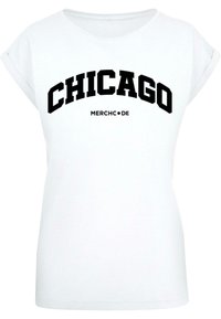 Witte t-shirt met korte mouwen, met bold zwarte tekst "CHICAGO" en daaronder in kleinere tekst "MERCH•DE". Gladde stof.
