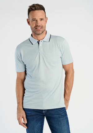Helles blaues Polohemd mit einem schwarz abgesetzten Kragen, einer Drei-Knopf-Leiste und kurzen Ärmeln; kombiniert mit dunklen blauen Jeans.