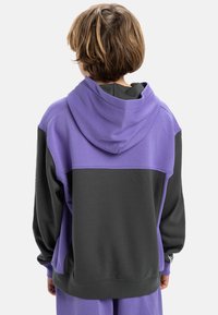 Sweatshirt à capuche violet et gris, avec une coupe décontractée, présentant un tissu texturé et des blocs de couleurs contrastées dans le dos.
